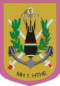 Znak 1. pluku pyrotechnické očisty maďarských ozbrojených sil.
(Magyar Honvédség 1. Honvéd Tűzszerész és Hadihajós Ezred)
(1st "Honved" EOD and Warship Regiment)